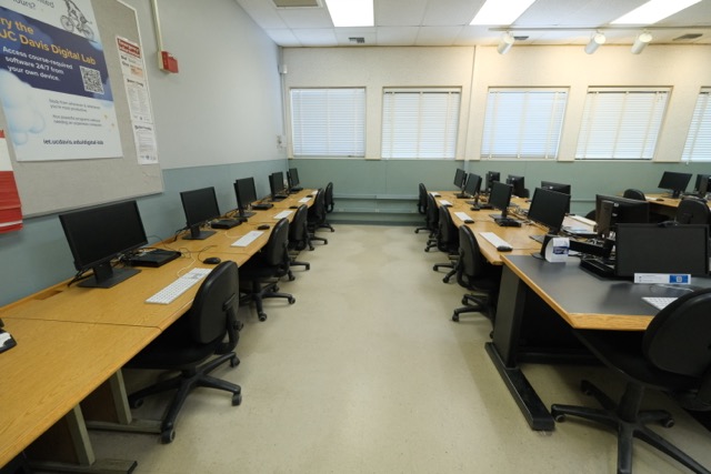 Empty computer lab with rows of desks, monitors and swivel chairs