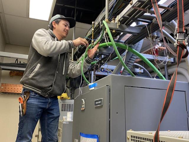 Man smiling while working on wiring inside a building