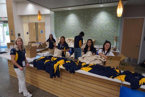 Volunteers smiling at the camera, preparing T-shirts for other volunteers.