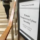 Sign for cybersecurity event, with student on stairs in background