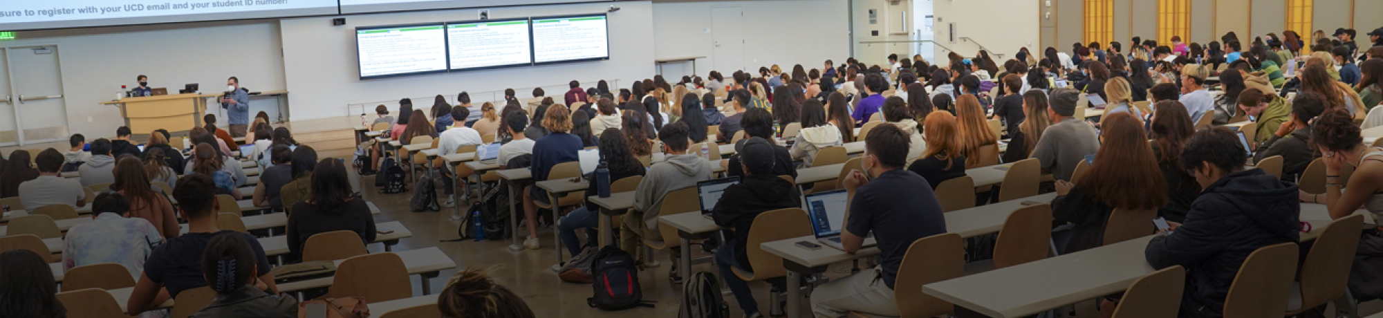 Large classroom with many students and large display screens